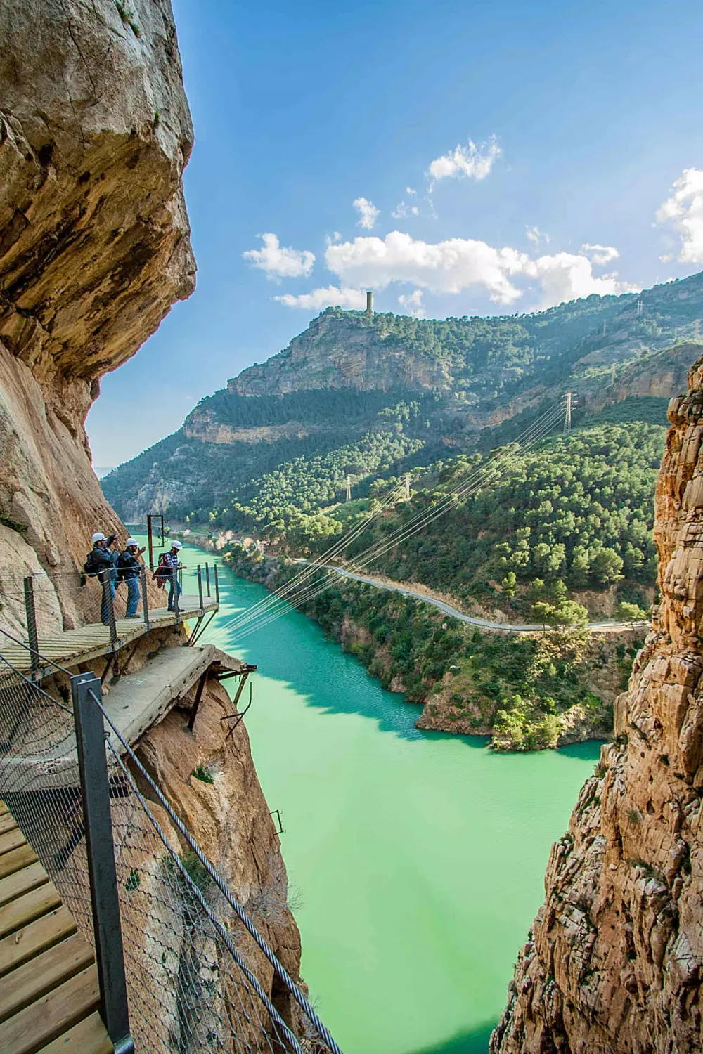 Hikers on the Caminito del Rey boardwalk suspended above the turquoise Guadalhorce River gorge, El Chorro, Málaga, Spain